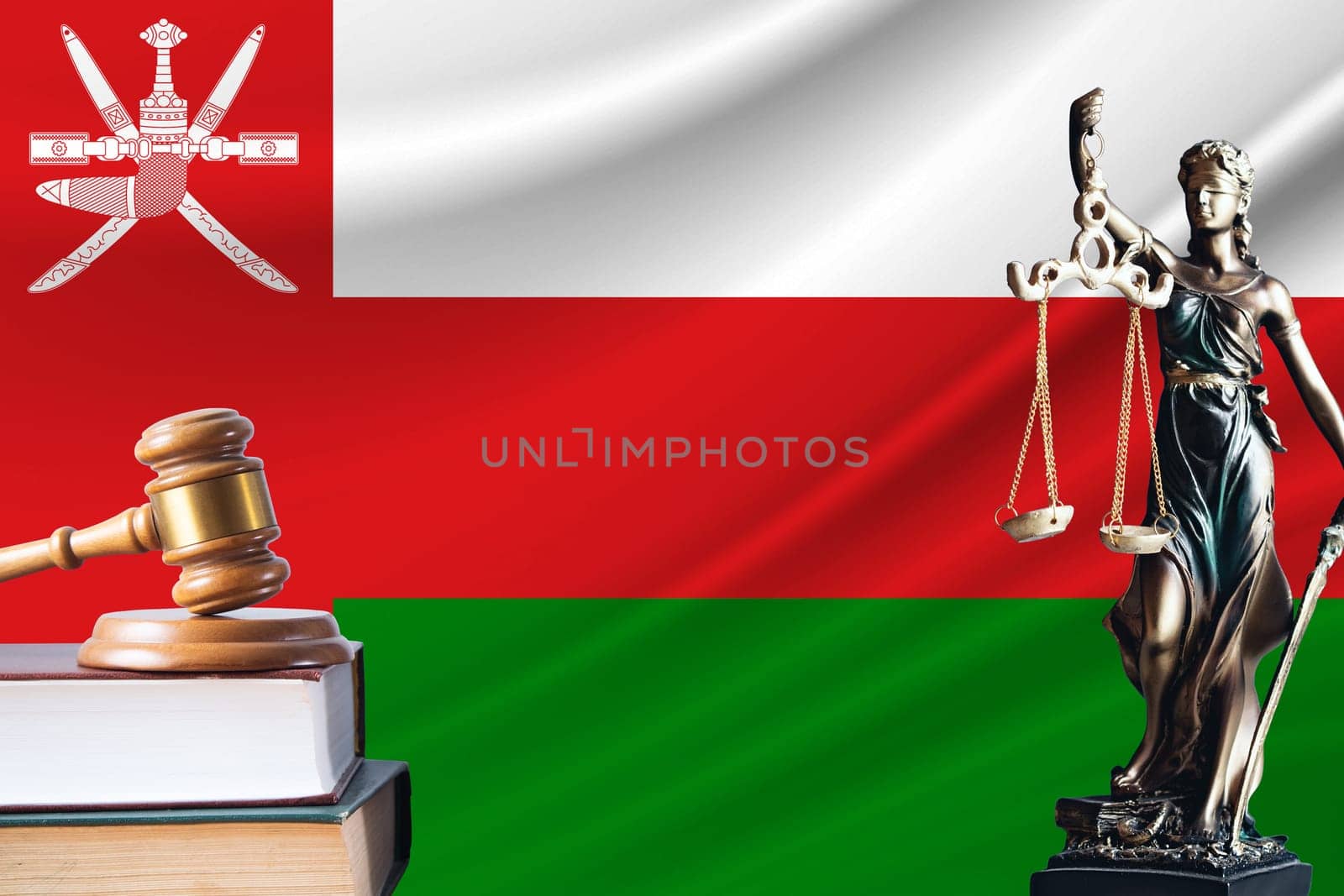 Law and justice in Oman. Statue of themis and the gavel of the judge against the background of the flag of Oman. Law and justice concept.