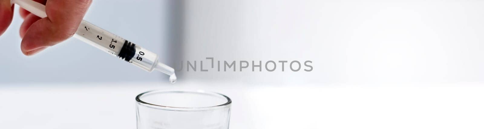 a researcher empties the liquid from a vial into a glass container to find a virus vaccine in a scientific analysis and research laboratory. Science and medical research