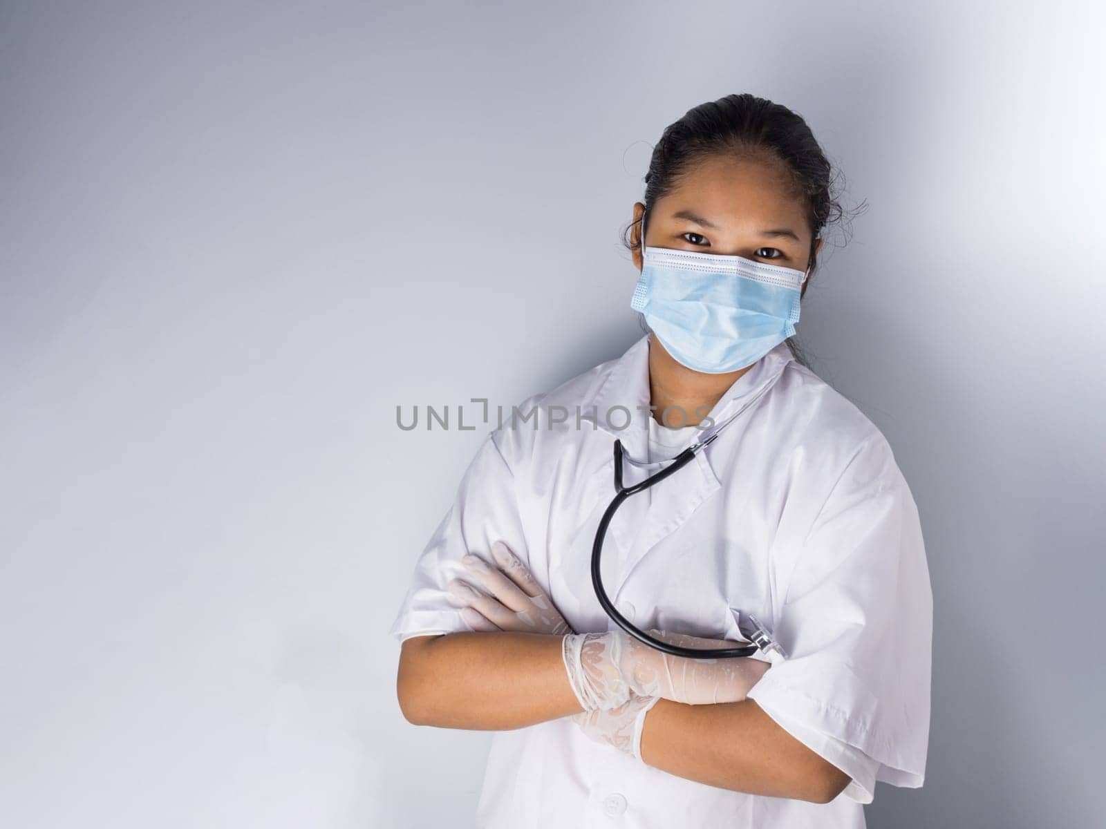 Studio portrait of a female doctor wearing a mask standing on a white background There was a slight light on his face.