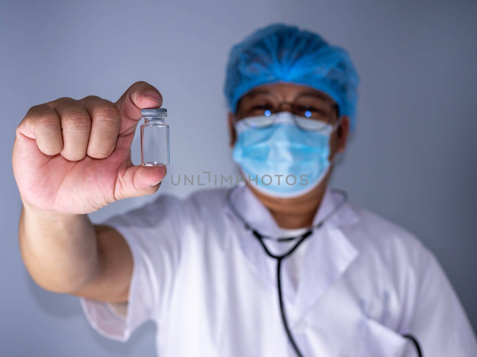 Portrait of a doctor wearing a mask and wearing a hat Stand holding an empty vaccine or pill bottle.Medical concept and treatment.