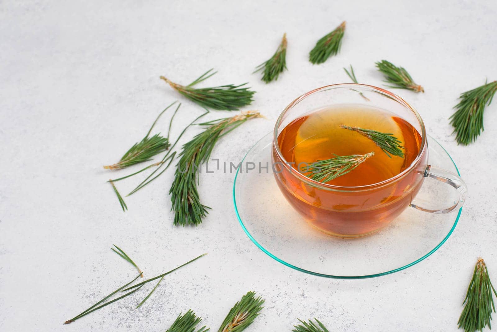 Pine needle tea in a cup on a white textured background, empty copy space for text, hot drink