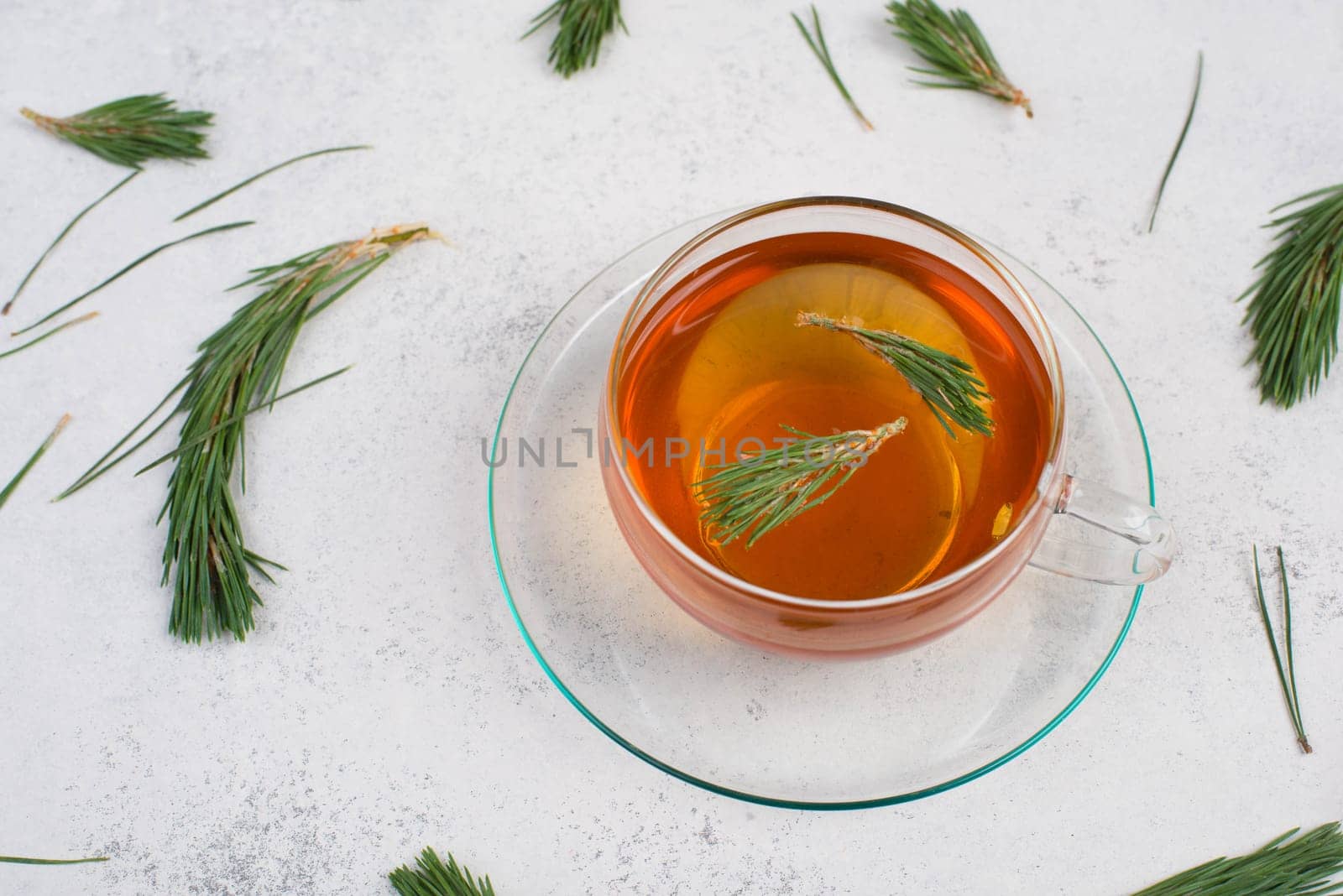 Pine needle tea in a cup on a white textured background, empty copy space for text, hot drink