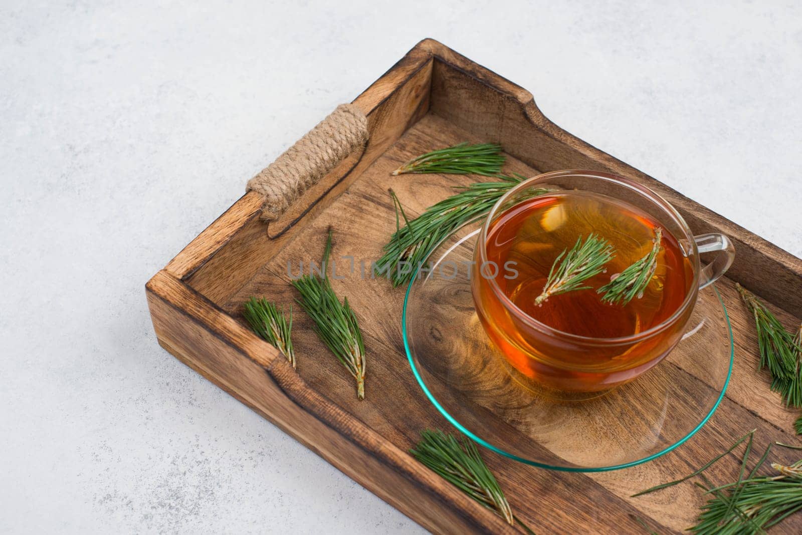 Pine needle tea in a cup on a white textured background, empty copy space for text, hot drink
