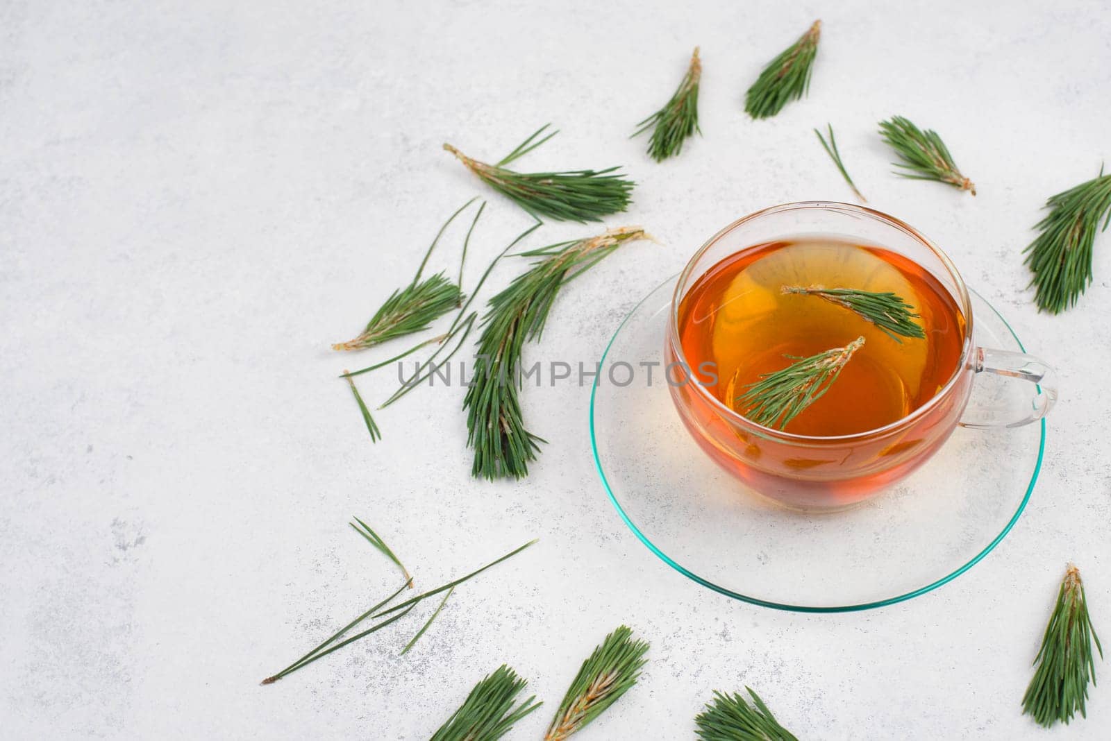 Pine needle tea in a cup on a white textured background, empty copy space for text, hot drink
