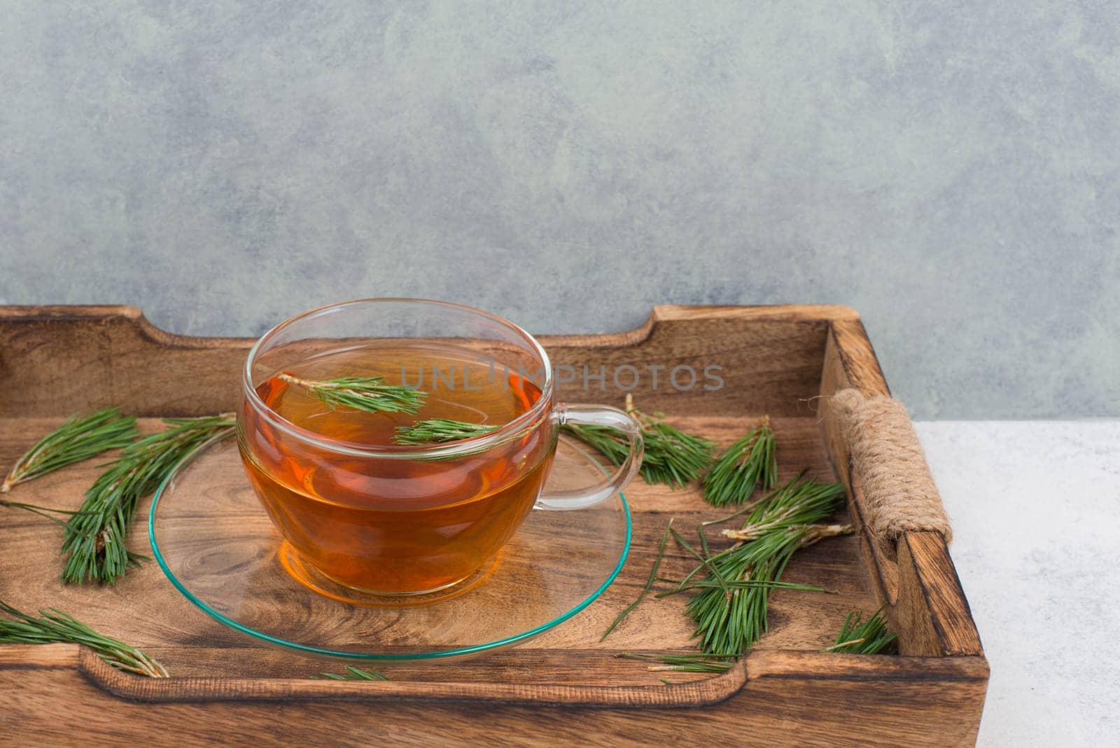 Pine needle tea in a cup on a white textured background, empty copy space for text, hot drink