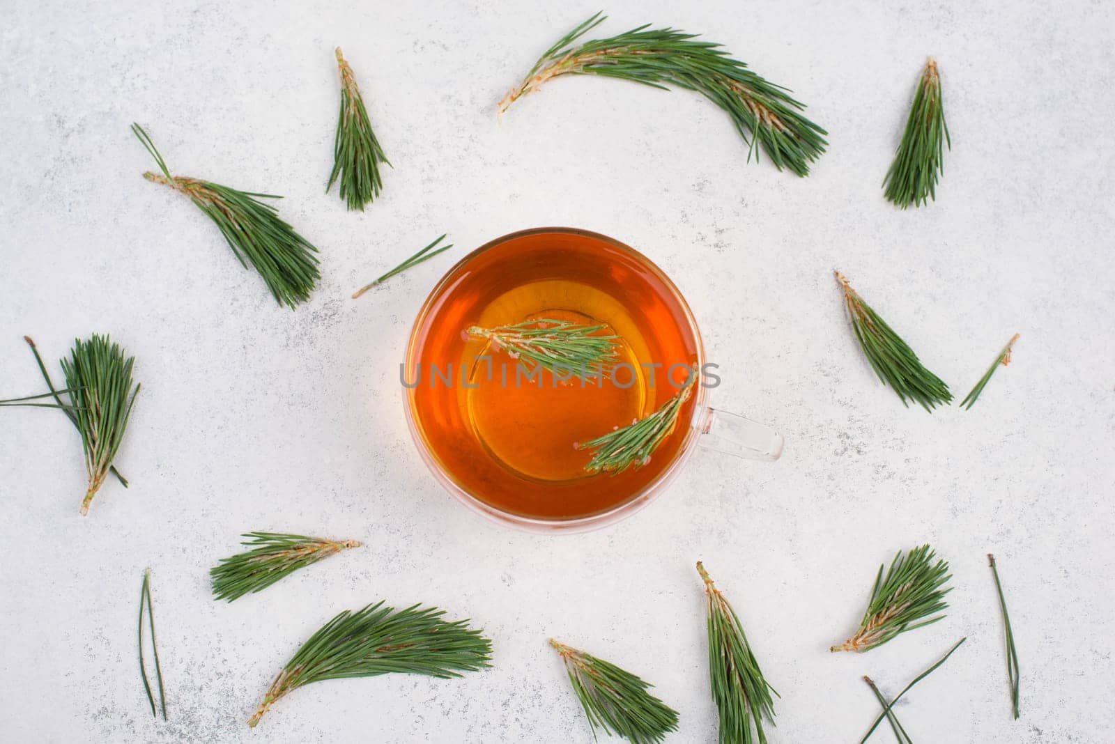 Pine needle tea in a cup on a white textured background, empty copy space for text, hot drink