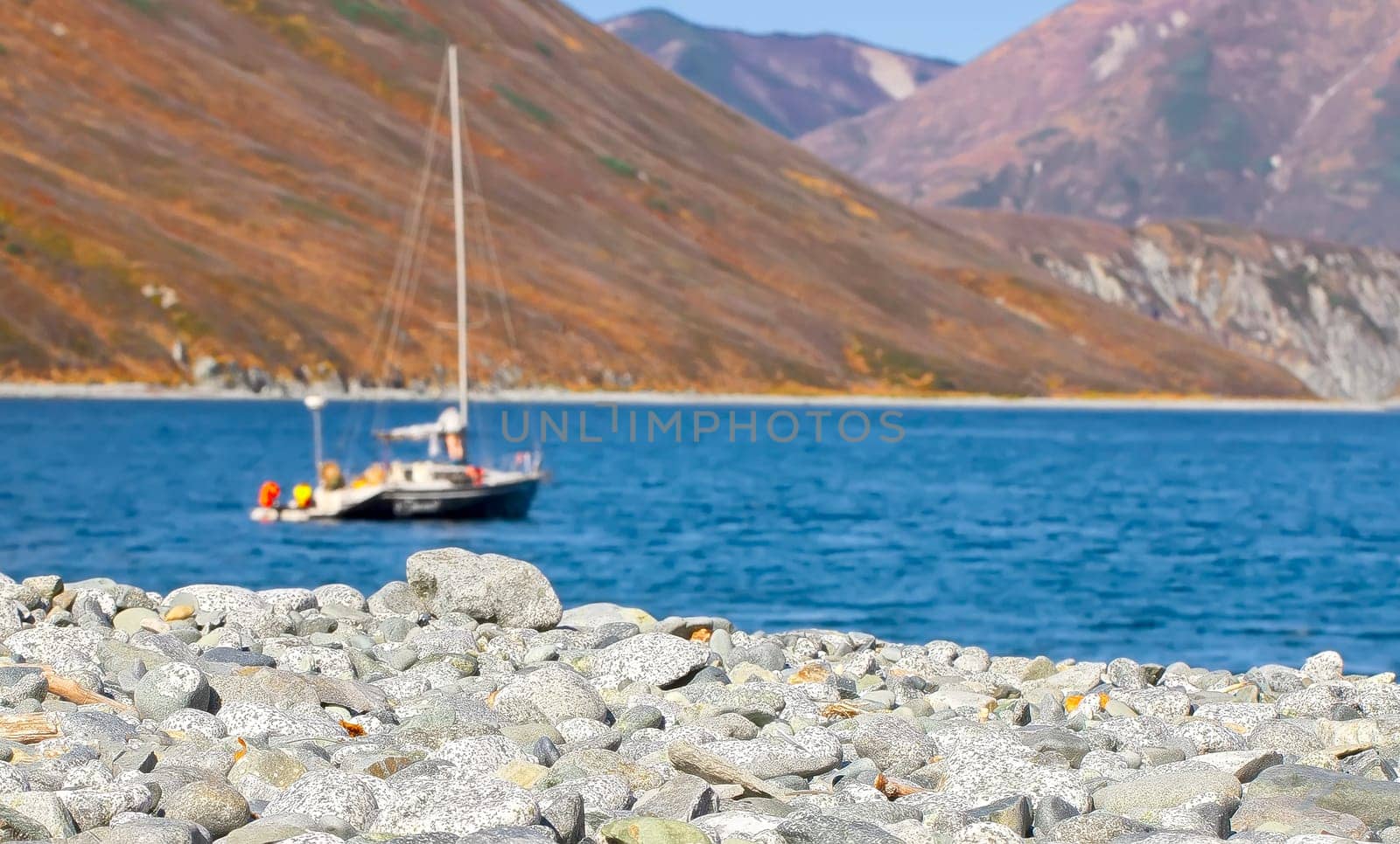 Selective focus. The Pebble beach in the Northern Bay of the Pacific ocean with one boat at anchor as a background. Selective focus