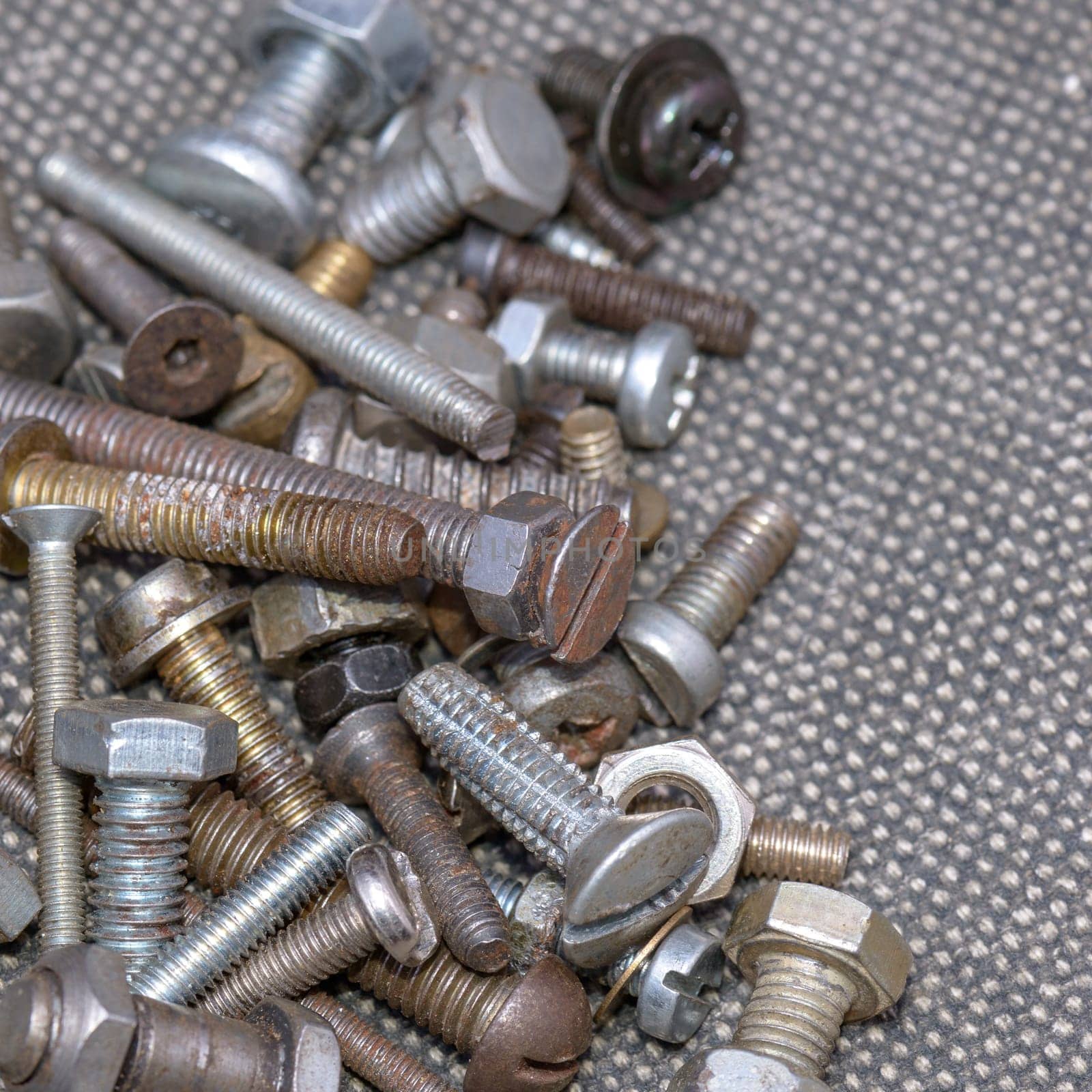 Several old screws on a grey texile background