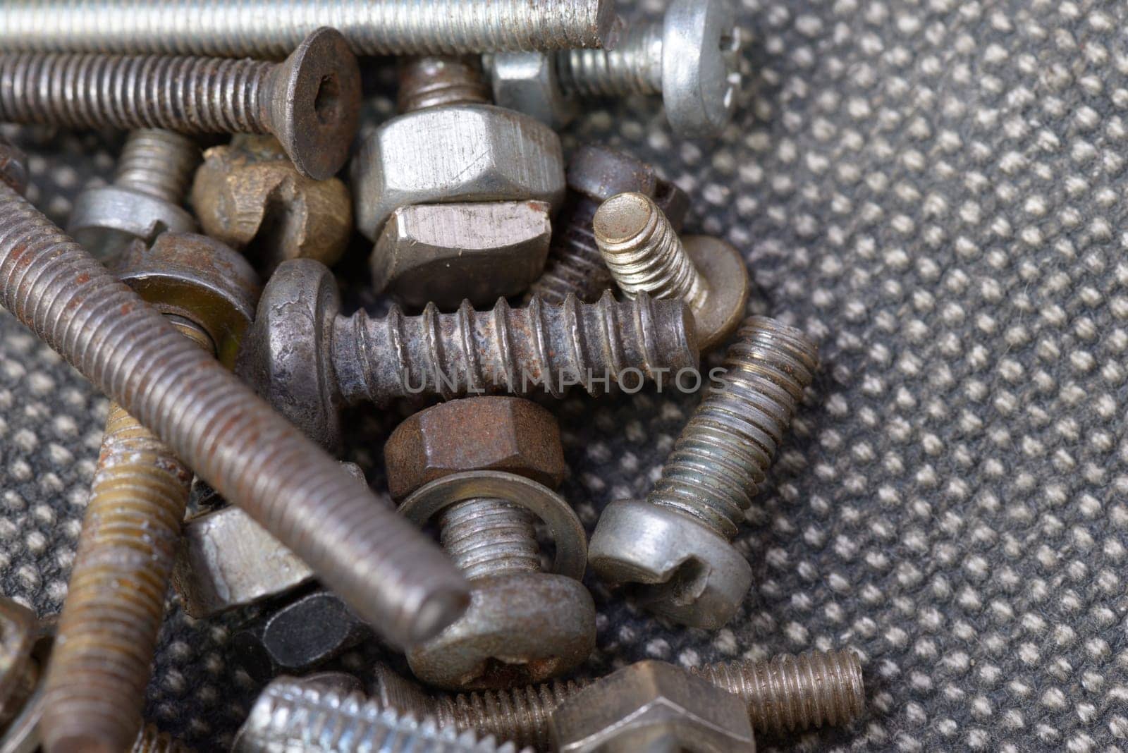 Several old screws on a grey texile background