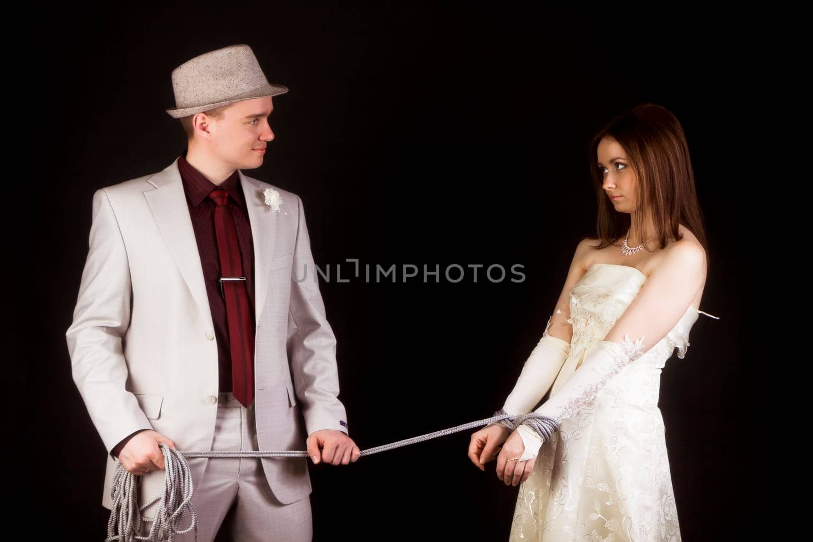 Wedding photo studio. Groom snared rope bride. fun