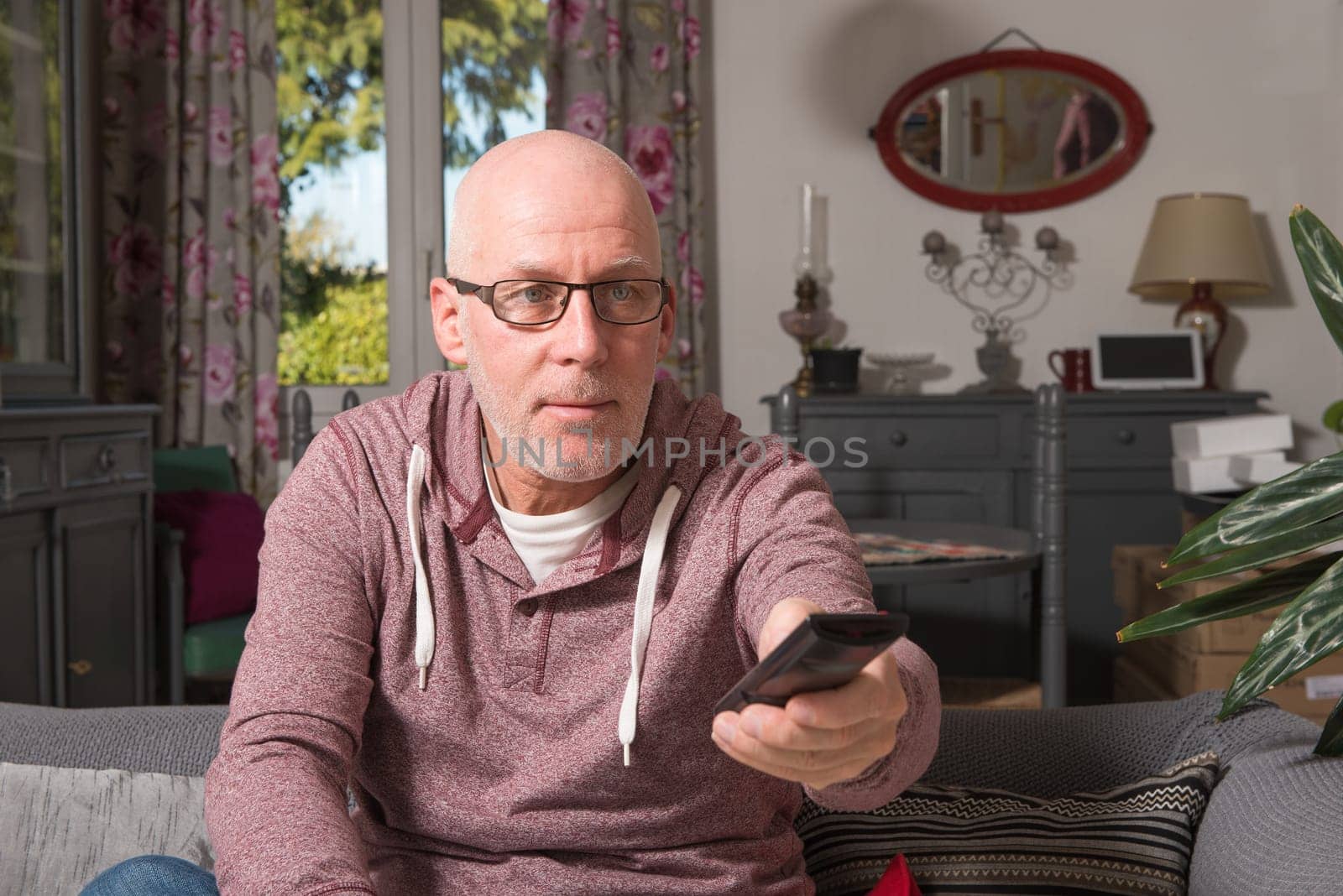 senior on a sofa in his home watch tv