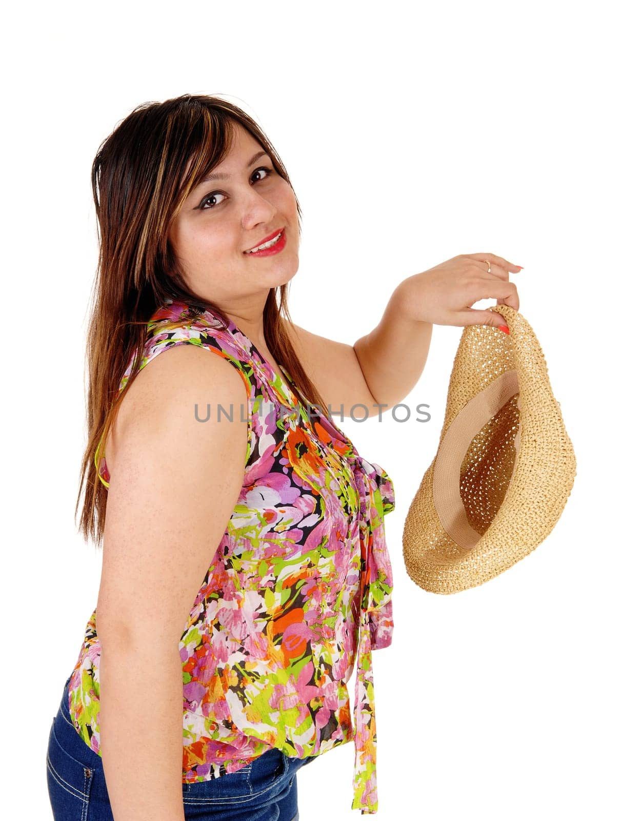 A young woman in jeans shorts holding her straw hat standing in profile,.isolated for white background..