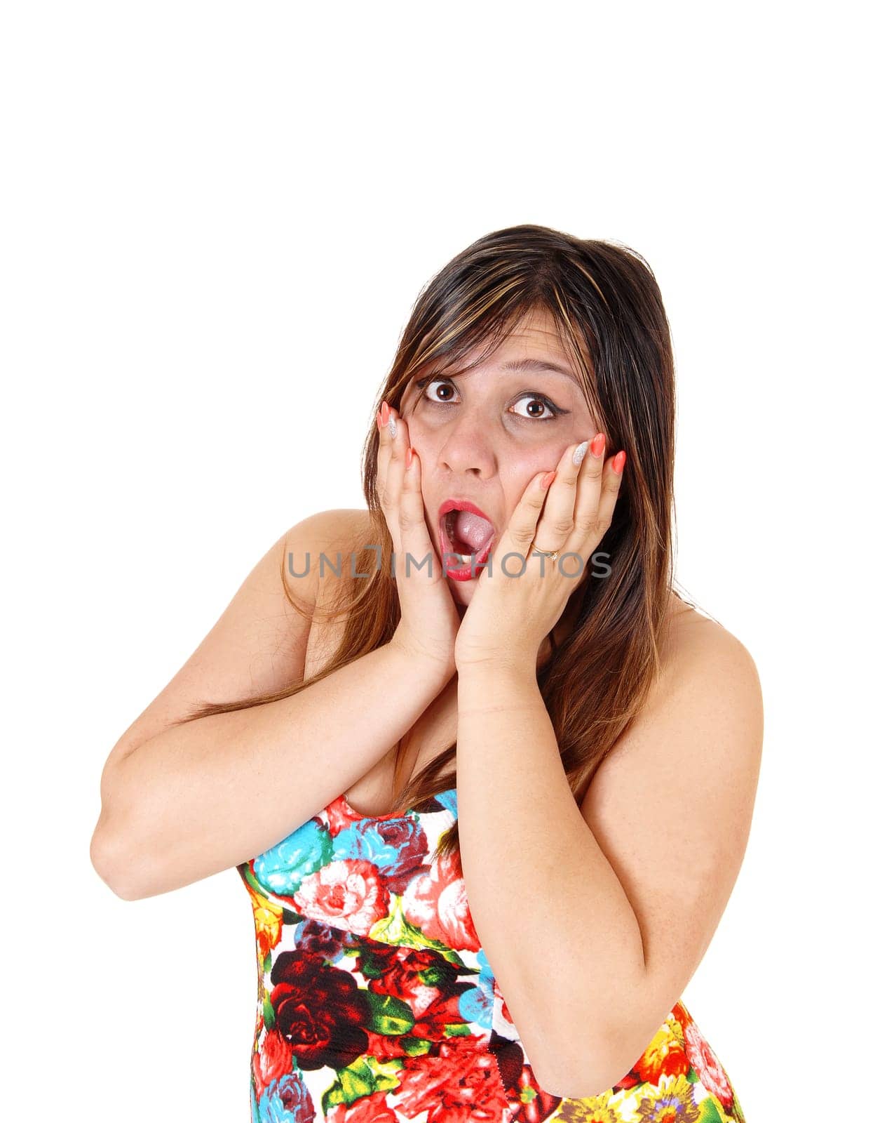 A scared young woman in a colourful short summer dress standing in profile.holding her hands on her face, isolated for white background..