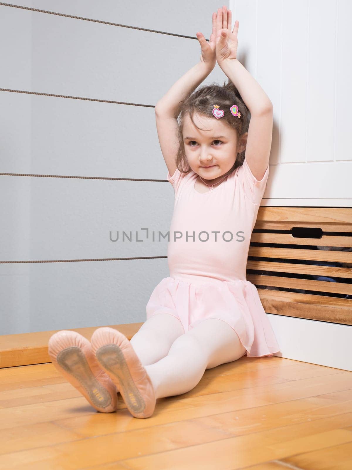 Little girl wearing a ballet dress is practicing ballet in a dance studio
