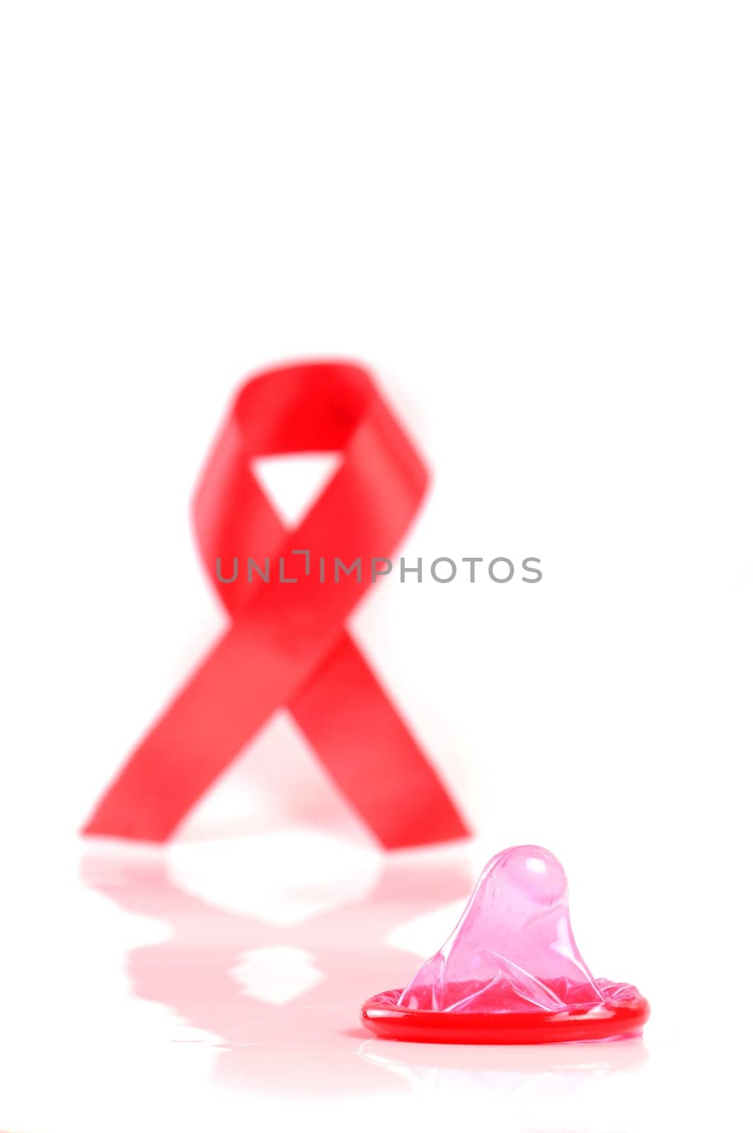 Aids ribbon and condom on white background.