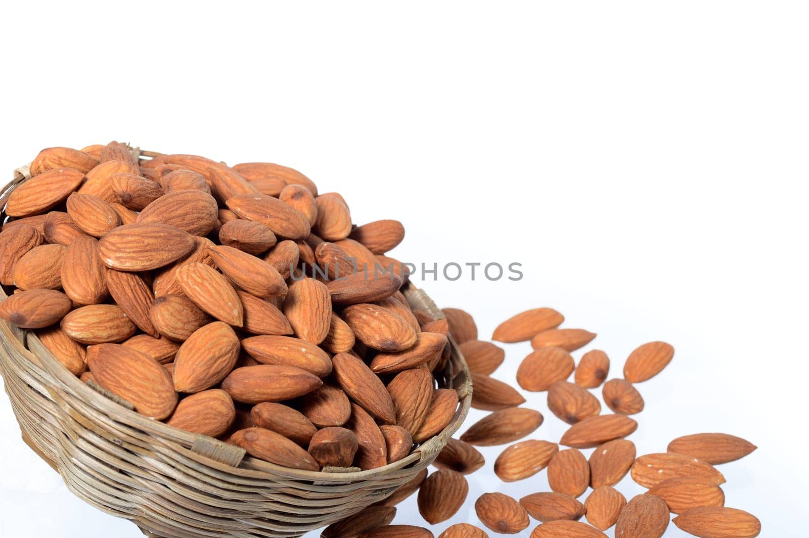 Almonds in a wooden basket with heap isolated on a white background