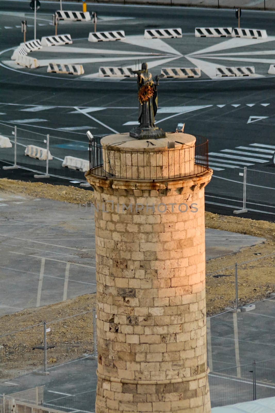 Ancient watchtower with a statue overlooking the sea in Civitavecchia port. A historic maritime structure in a busy harbor. Concept: seafaring heritage