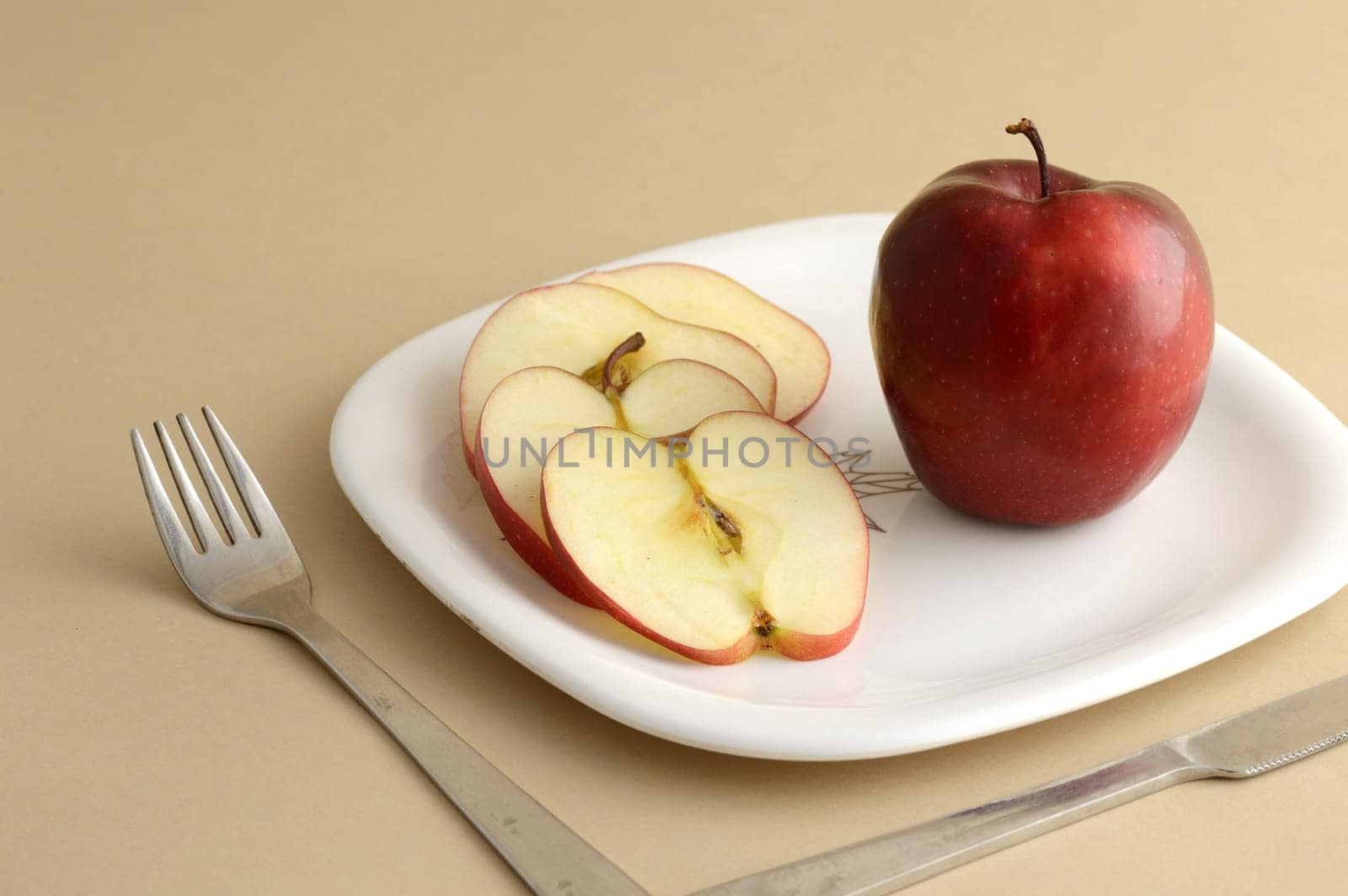Delicious apple and slice in white plate with knife and fork