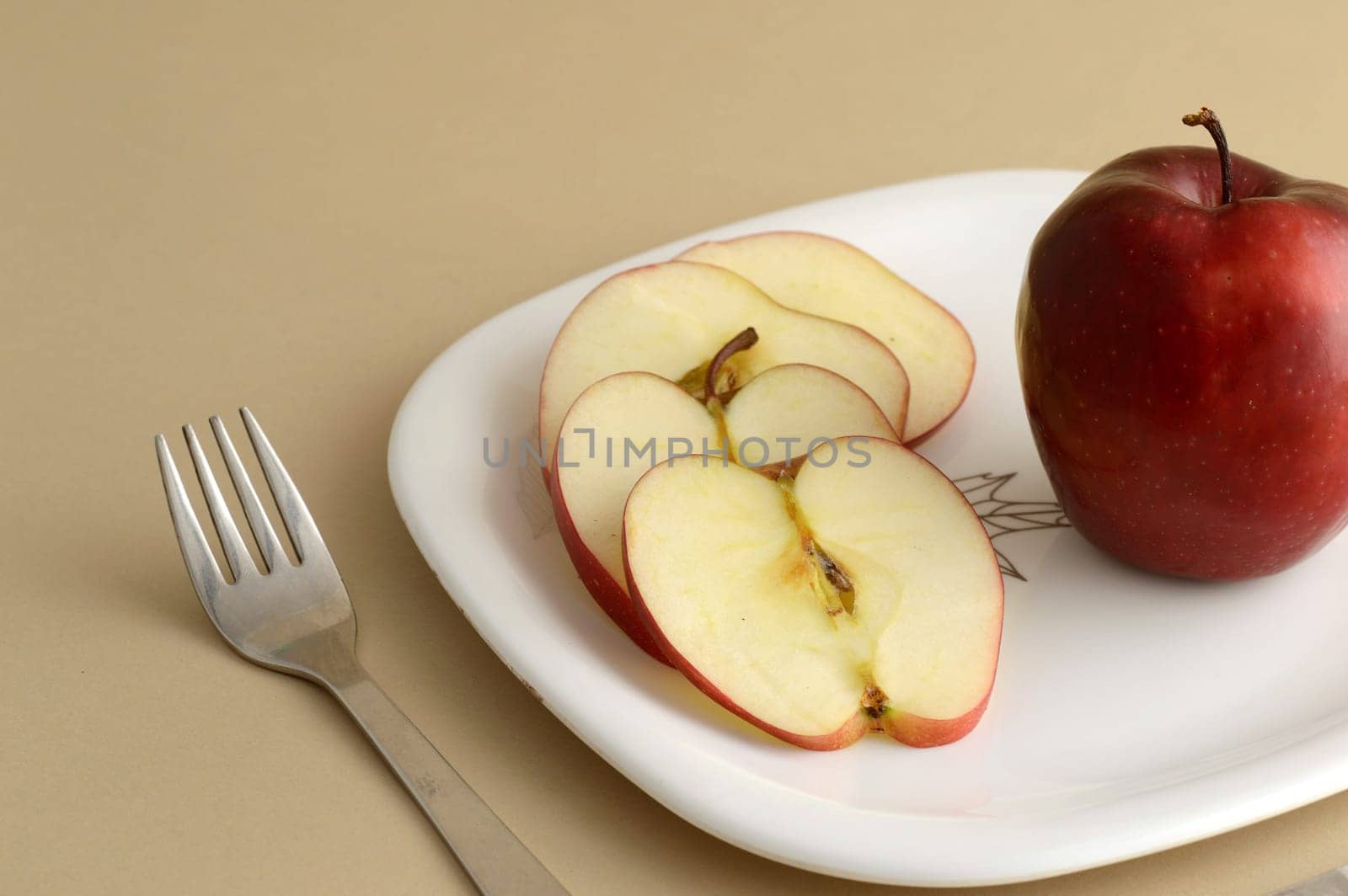 Delicious apple and slice in white plate with knife and fork