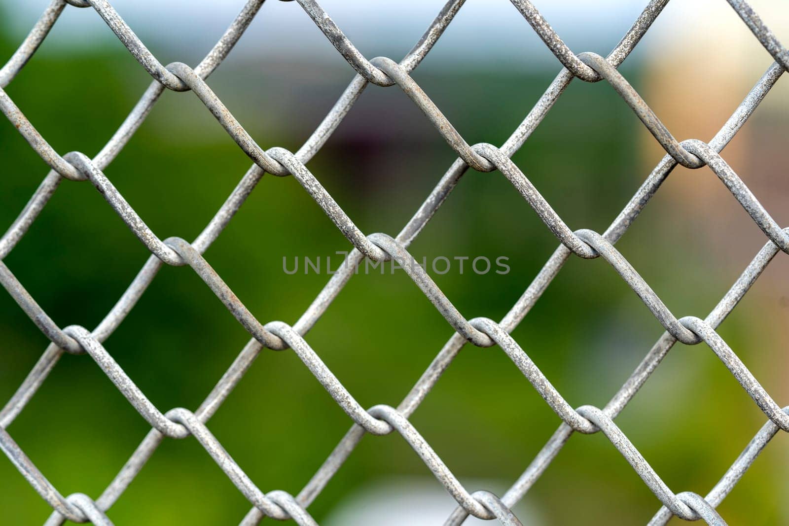 A close up picture of a rusty wire fence with colorful background