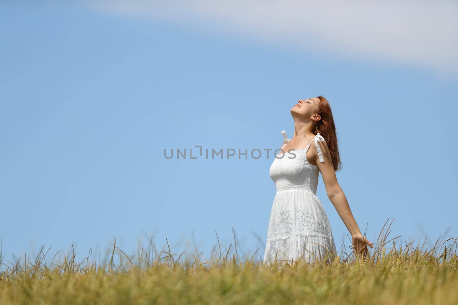 Woman with white dress breathing fresh air in a wheat field