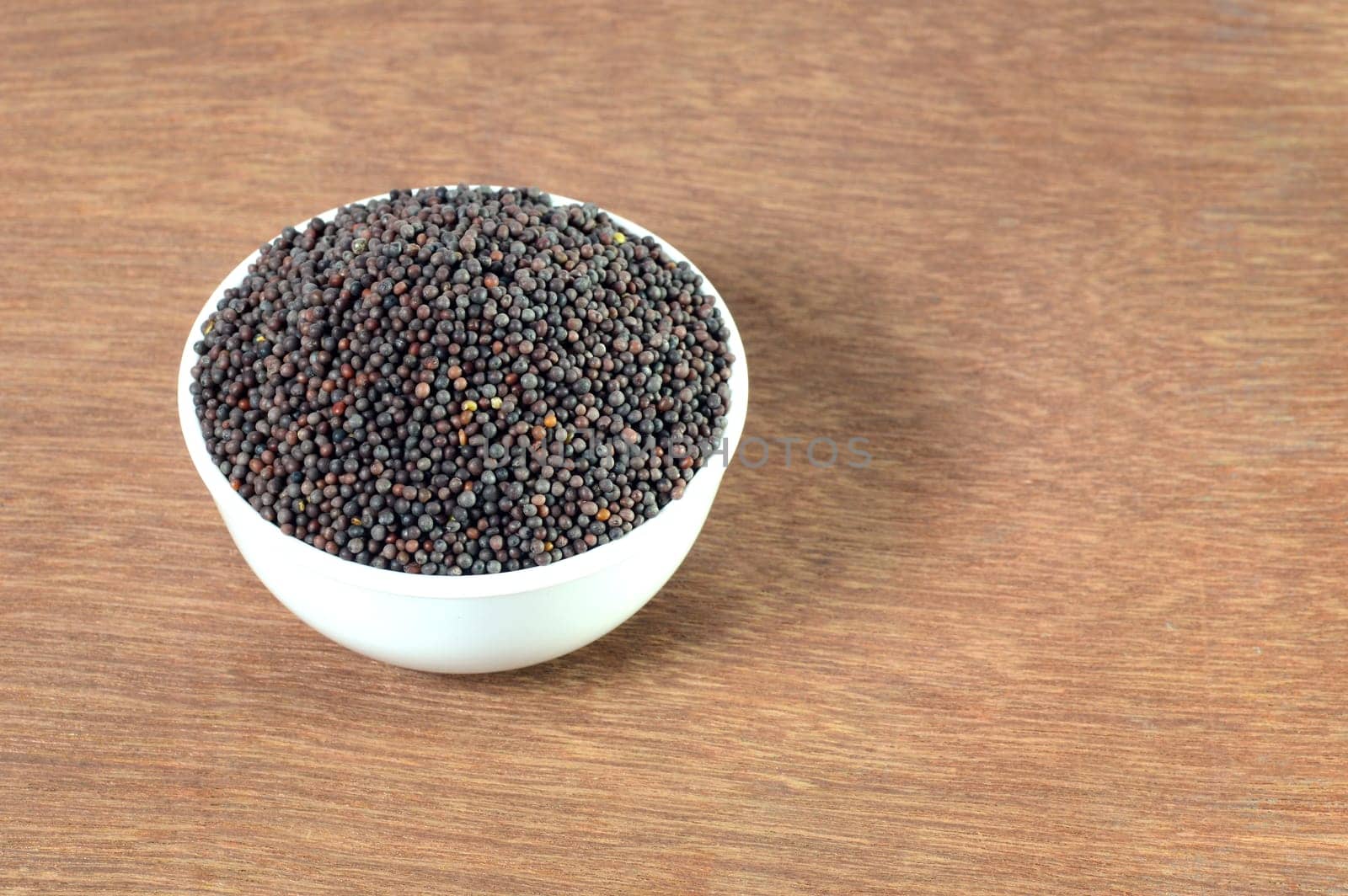 Brown Mustard Seeds in bowl on wooden background