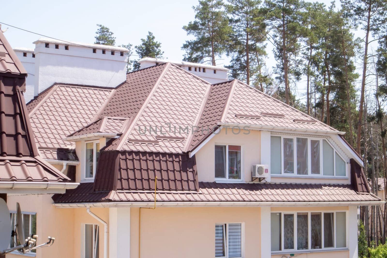 Roof on residential property with new brown corrugated metal roof tiles. Modern metal roof. Metal roofing
