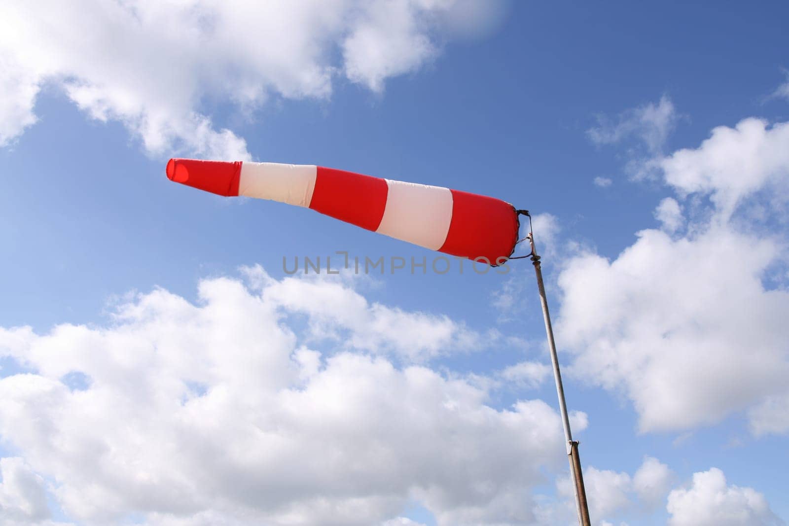 Windsock flag with red and white stripes on blue sky background