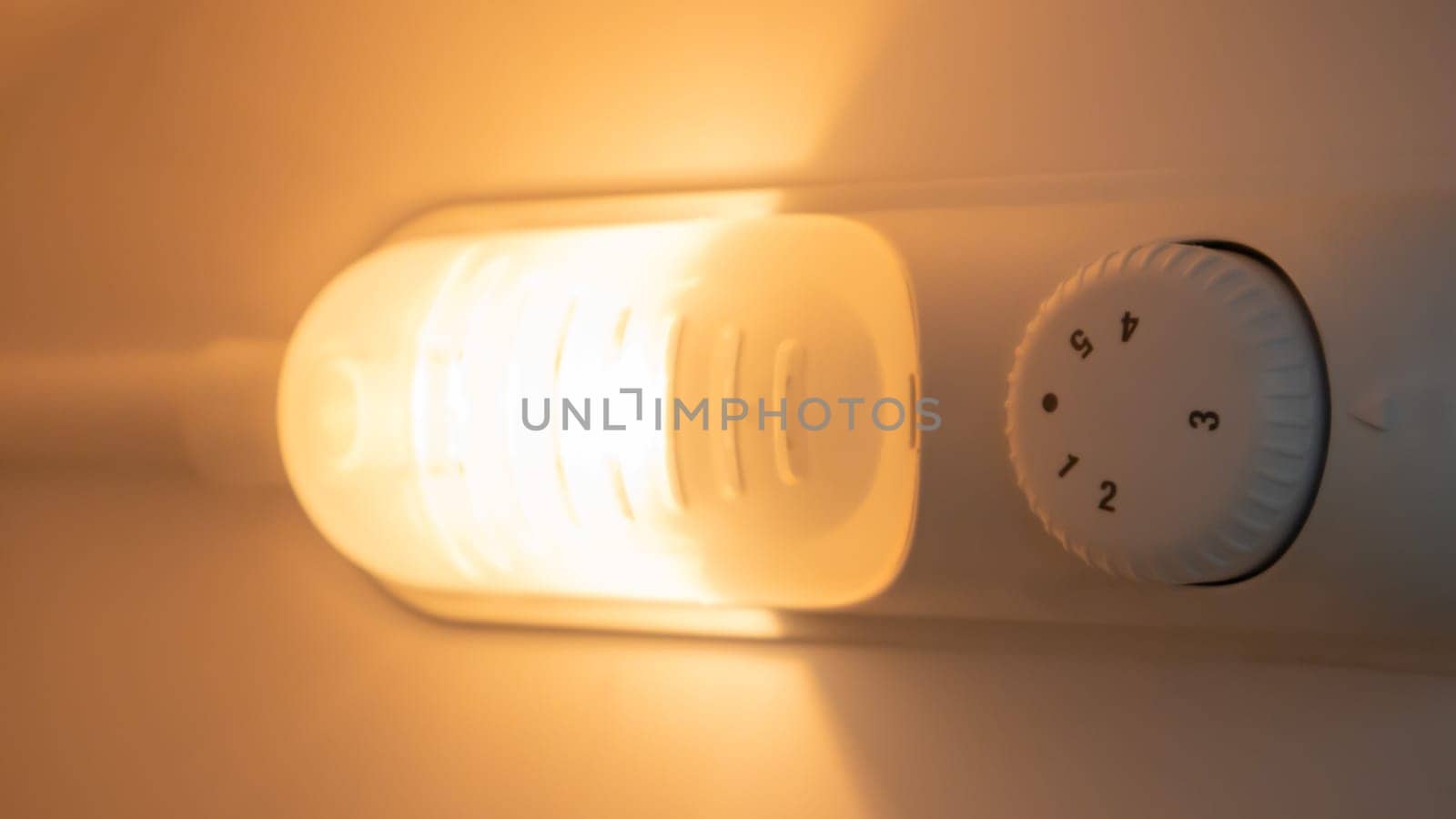 Orange light inside the refrigerator close-up. A lamp that turns on when the door is open to improve vision. Household appliances concept, changing the lamp in the freezer