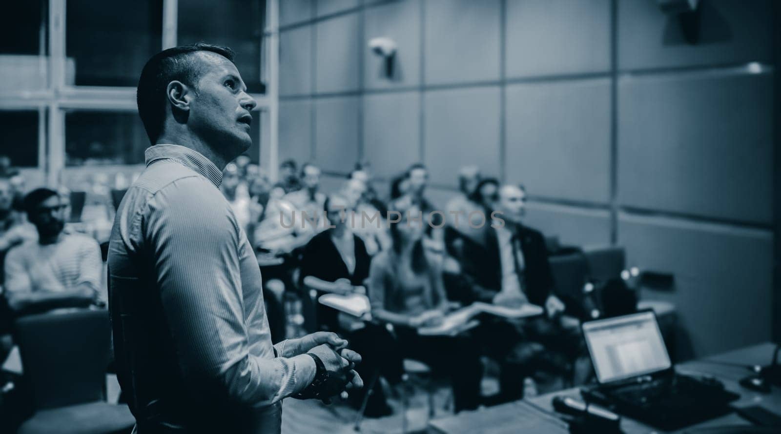 Speaker giving a talk on corporate business conference. Unrecognizable people in audience at conference hall. Business and Entrepreneurship event.