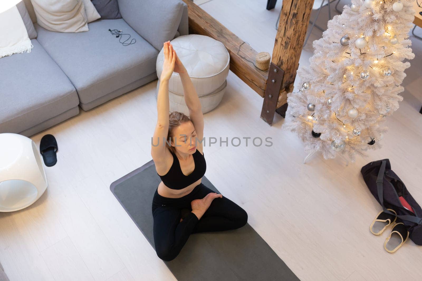 Beautiful blonde woman doing home workout indoors. Woman practice yoga at home. Fit girl using workout tutorials for healthy active lifestyle. Woman using quarantine for home workouts and stretching