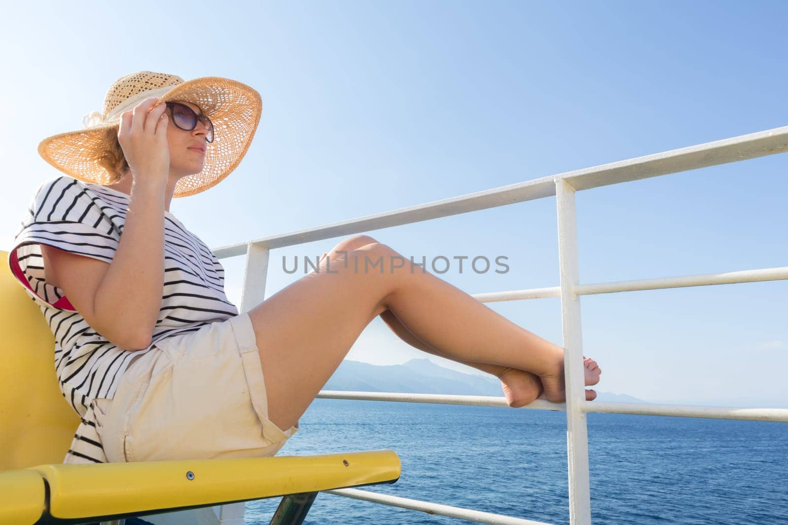 Beautiful, romantic blonde woman relaxeing on summer vacations traveling by cruse ship ferry boat. Summer vacation lifestyle.