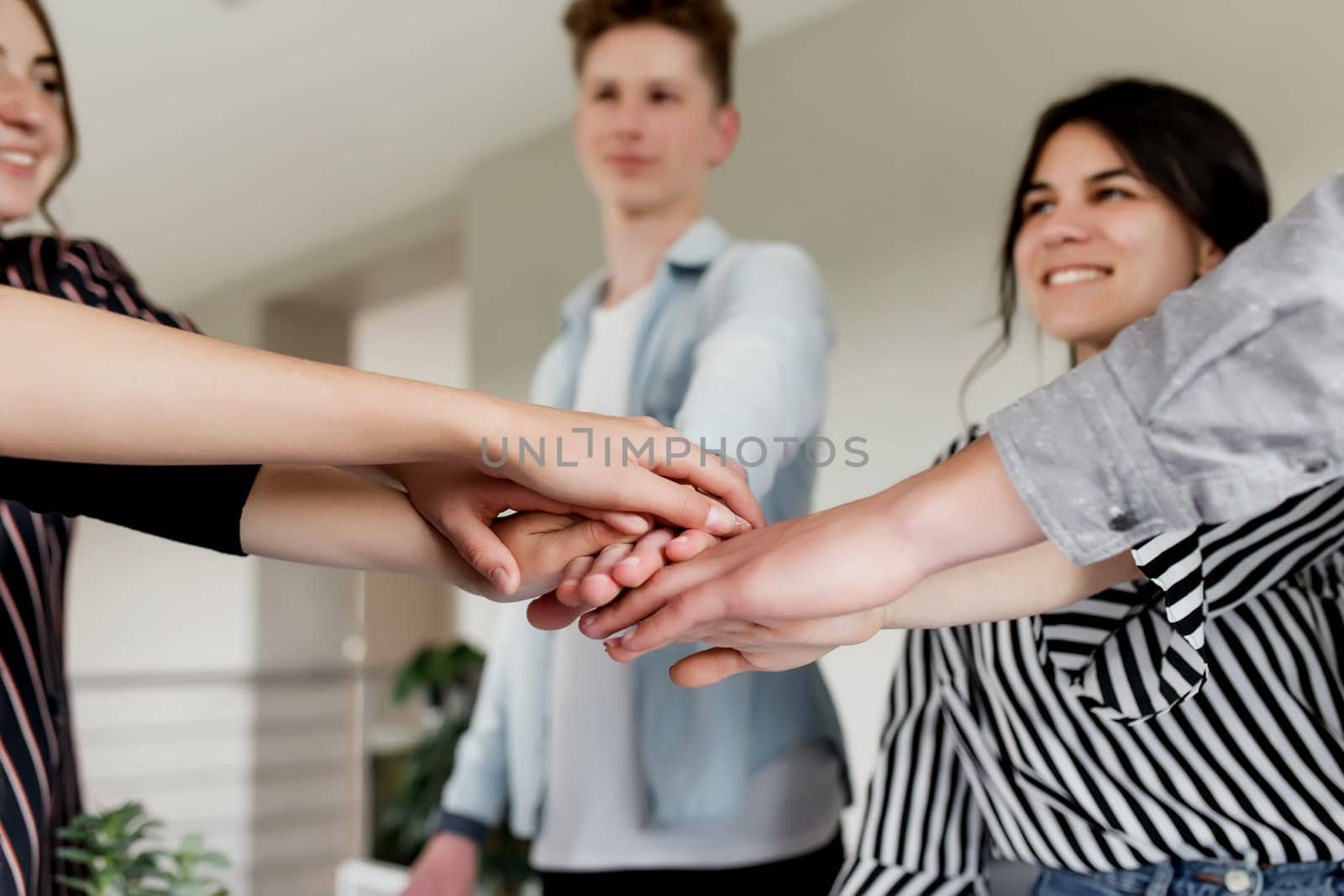Friendly group of people doing handshake and cross hands. Friendship, agreement, cooperation concept with young teens crossing their hands