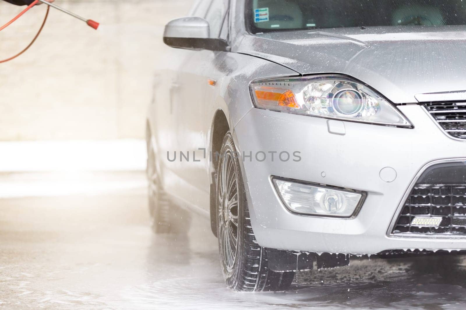 High pressure cleaning car in exterior washbasin. Touchless washing automobile with water and soap in carwash. Vehicle purifying using clearing equipment.