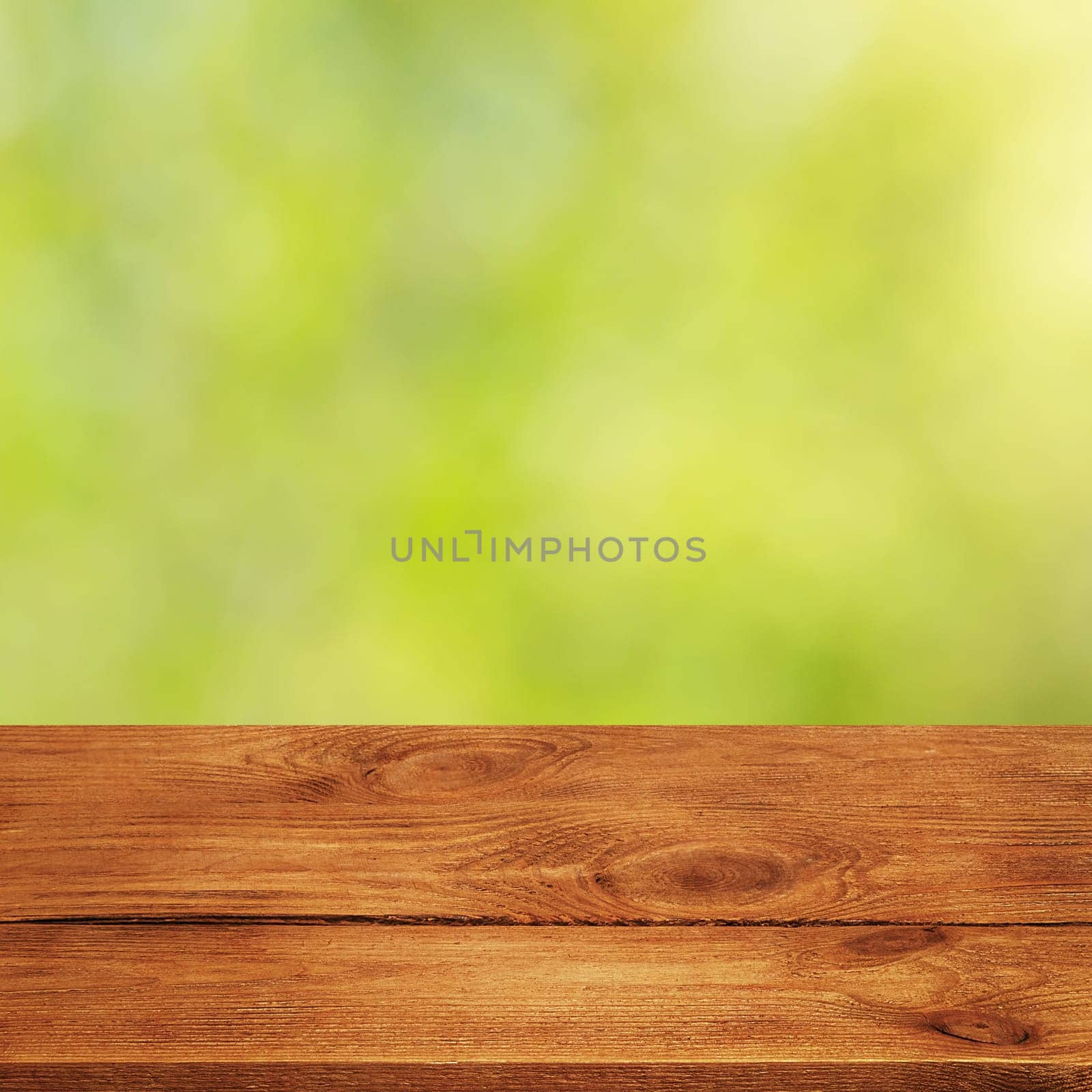 Background with blurred green leaves and empty wooden planks in the foreground. For product demonstrations, free space, layout, mockup, perspective board, background board.