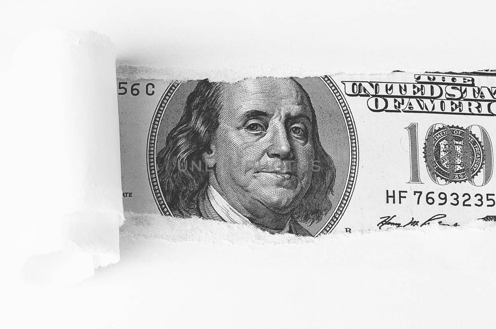 The face of Benjamin Franklin on a hundred-dollar bill, from a torn window in white paper. Background, white. Isolated. Close-up. A hundred-dollar American bill with the eyes of Benjamin Franklin. Black and white style. Place for logo, lettering, sign, template, mockup.