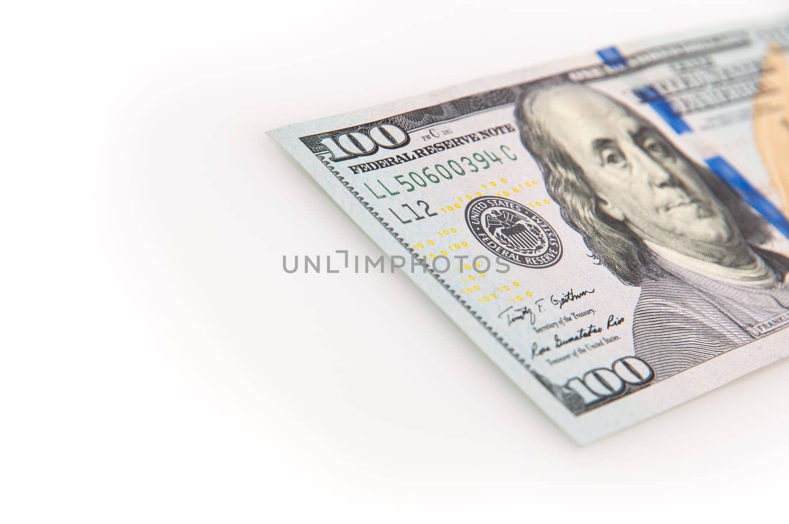 A hundred-dollar bill on a white background. The one hundred North American dollars bill is not fully positioned diagonally. Selective focus on a portion of the 100 bill. Color style. Place for logo, lettering, layout, layout.