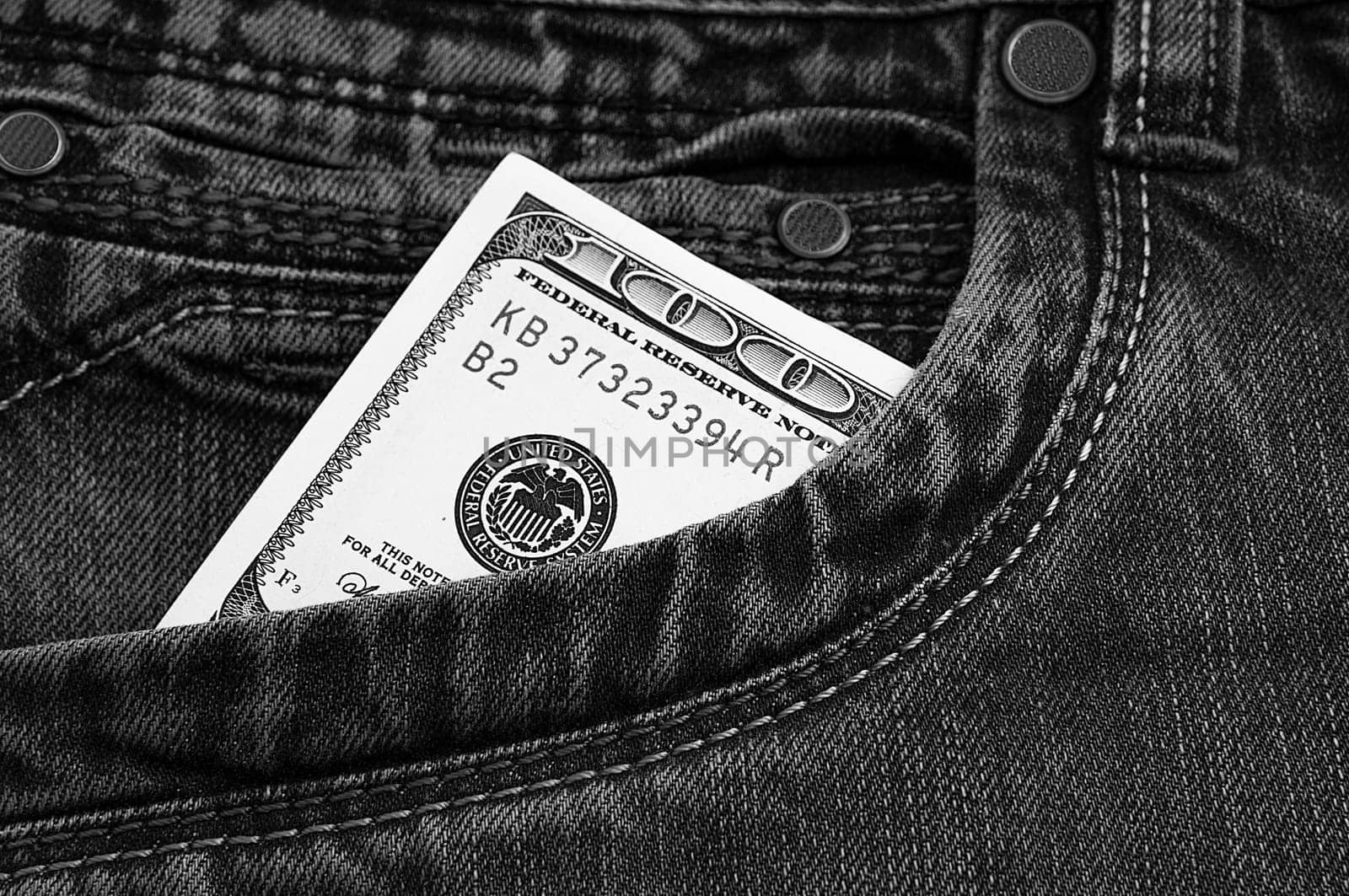 A hundred-dollar bill in the pocket of his jeans. The one hundred American dollar bill is sticking out. One bill is US dollars. Black and white style.