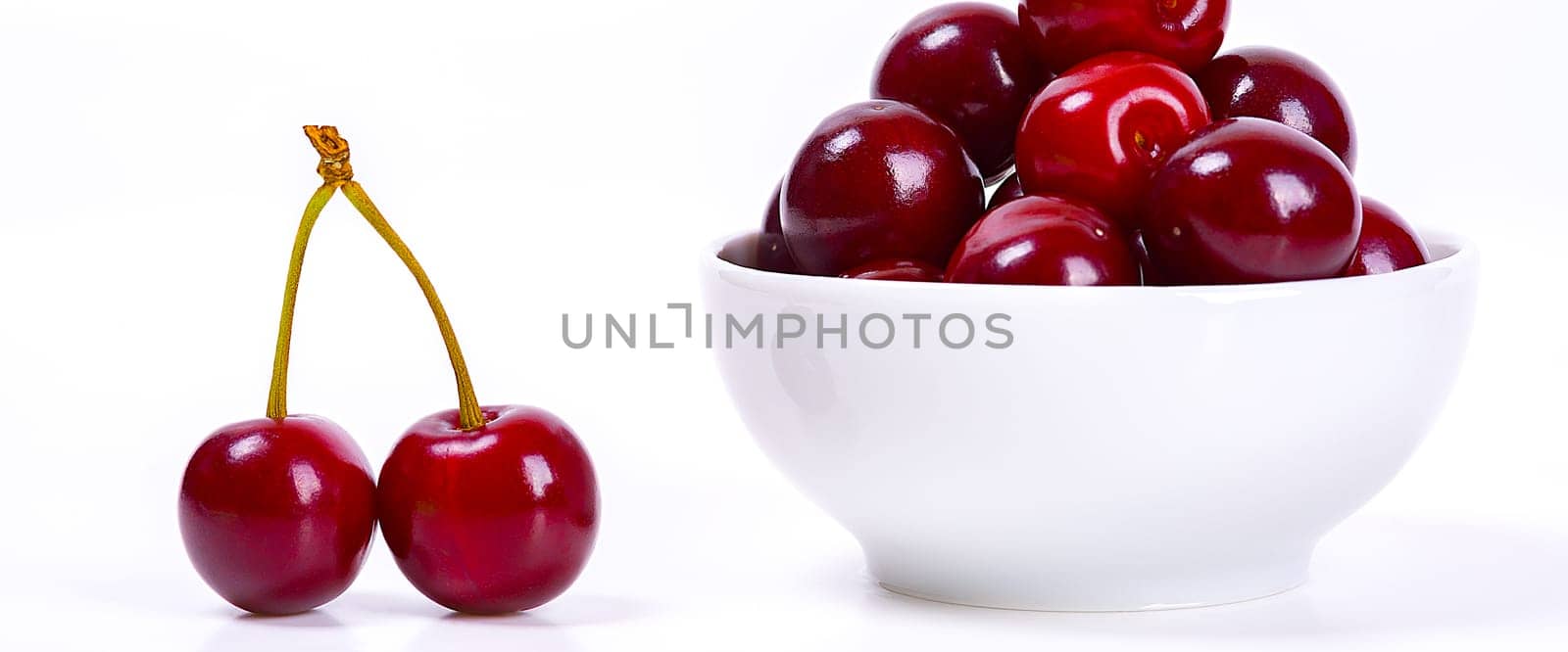 Cherry berries in a white cup on a white background. Isolated. Ripe cherries. Red delicious cherry. Place for advertising, lettering, logo, text, layout, mockup.