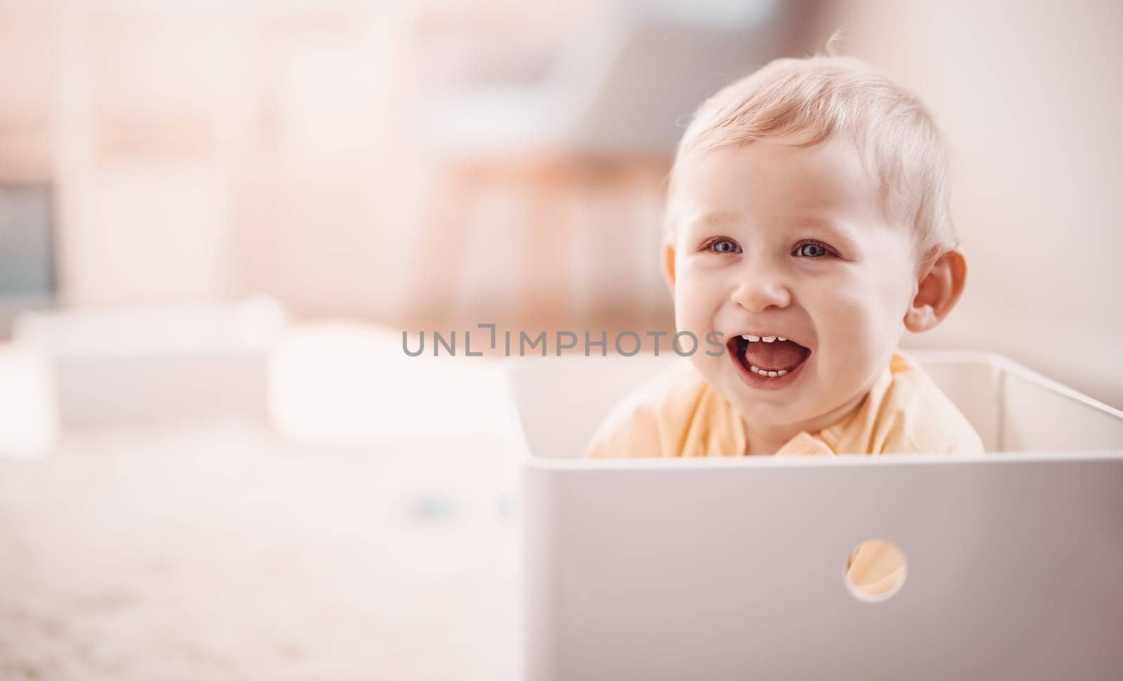 Cute boy sitting in the white plastic box. Baby laughing. Concept of the family and mother's love.