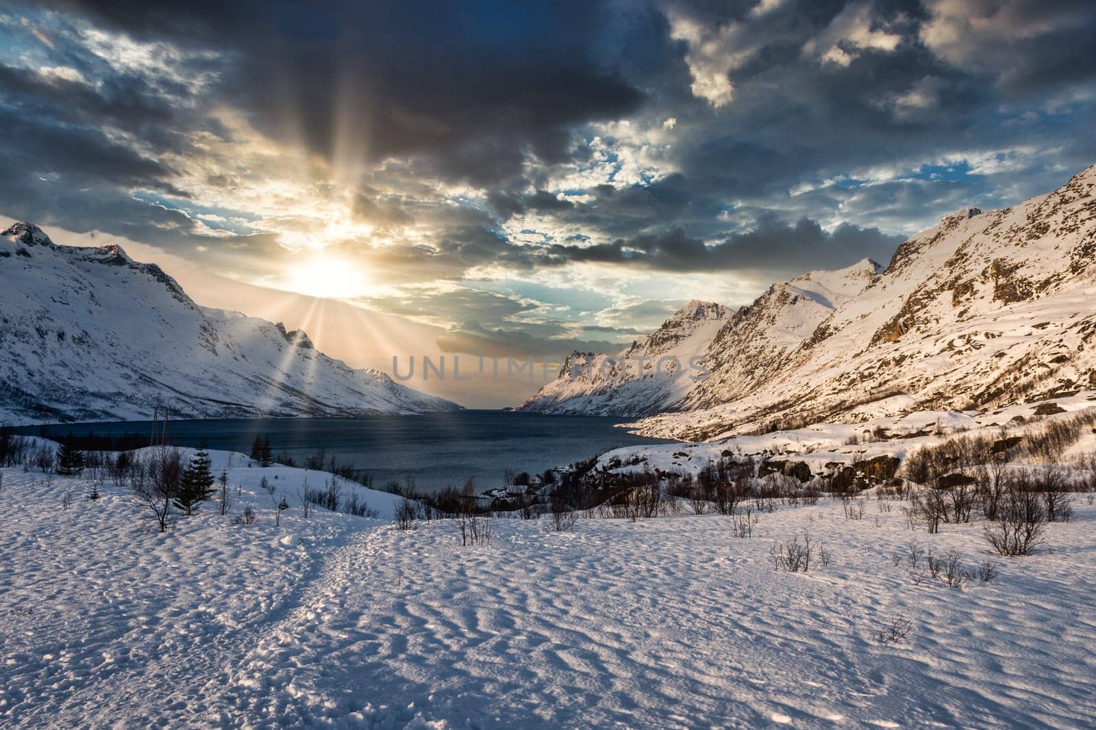 Frozen mountain lake landscape on a mountain near tromso, norway during sunrise with cloudy sky