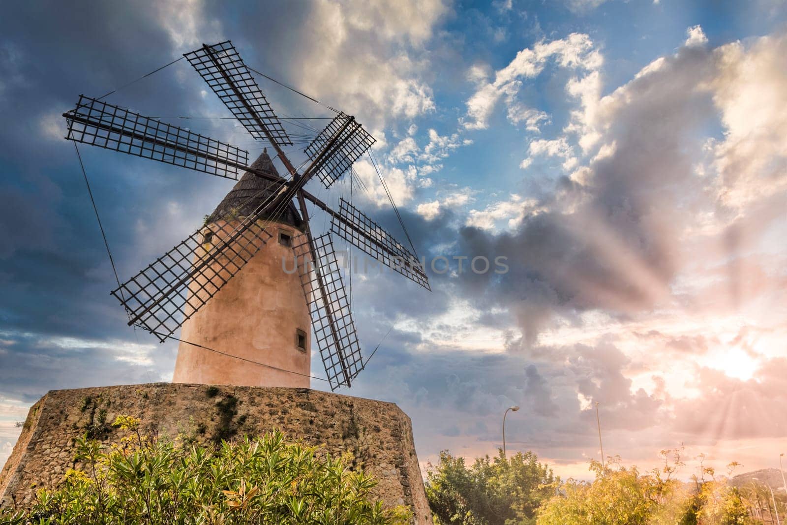 Old windmill near palma in mallorca, majorca during sunrise with clouds, low angle view
