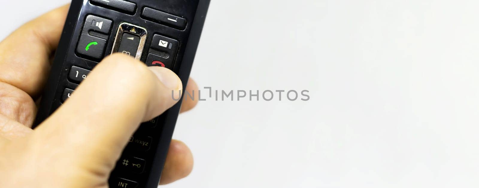 Thumb pushing the button with the red icon to reject or hang up a call on the phone. Landline telephony. Wireless phone. Copy space
