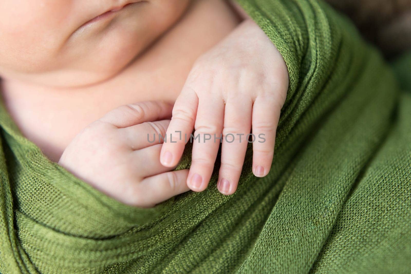 little baby hands newborn child on a green background
