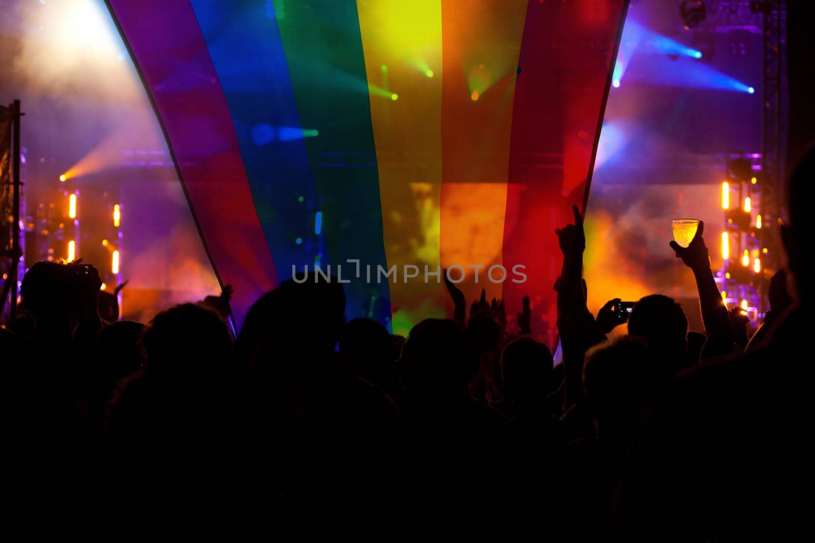 Pride community at a parade with hands raised and the LGBT flag - symbol of love and tolerance