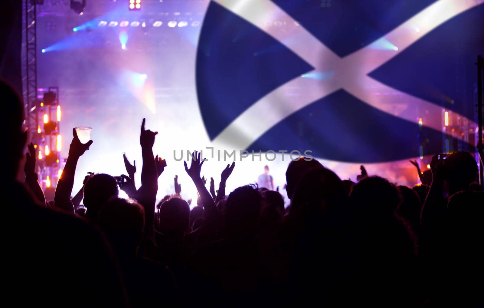 Soccer fans supporting Scotland - crowd celebrating in stadium with raised hands against Scotland flag