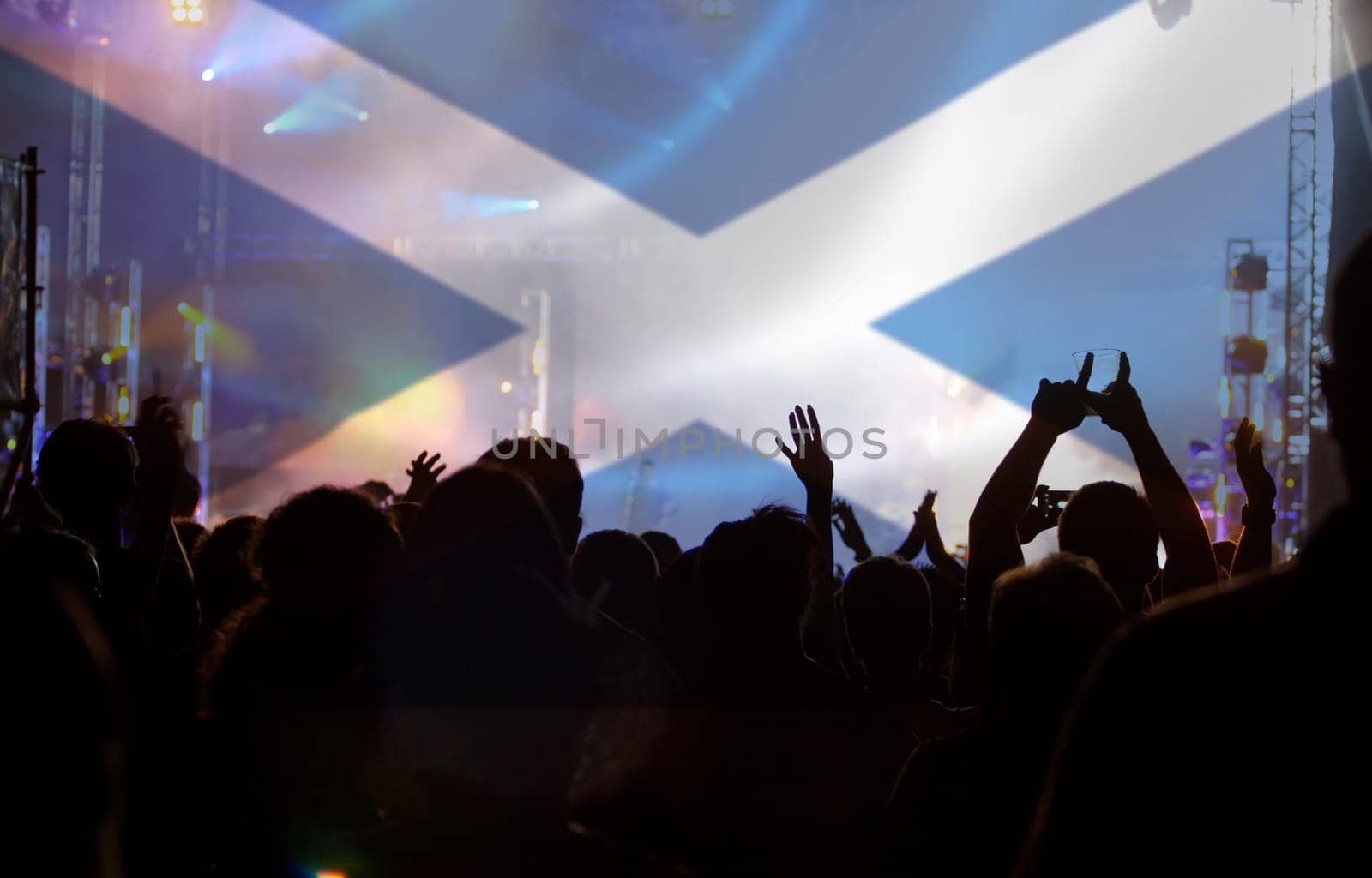 Soccer fans supporting Scotland - crowd celebrating in stadium with raised hands against Scotland flag