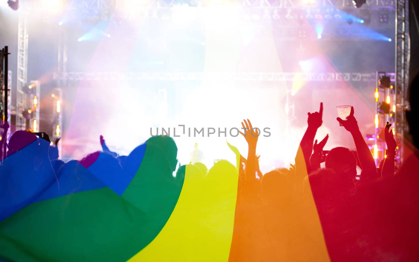 Pride community at a parade with hands raised and the LGBT flag - symbol of love and tolerance