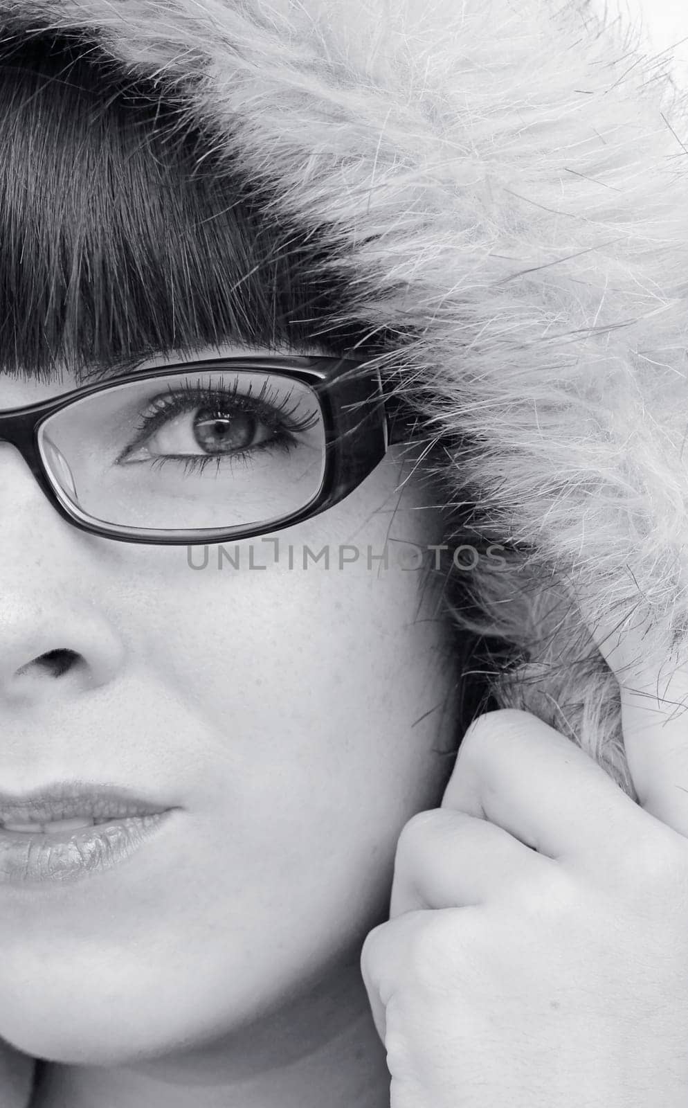 The face of a young woman with glasses and fur hood