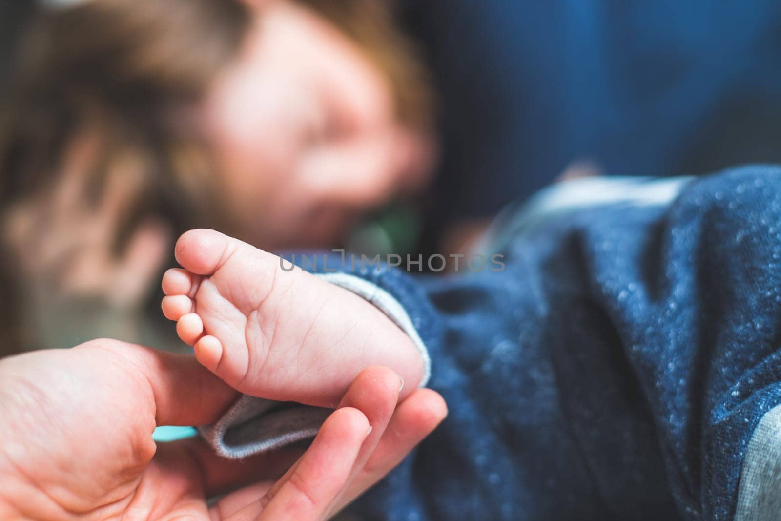Close up of mother’s hands, holding newborn baby feet.